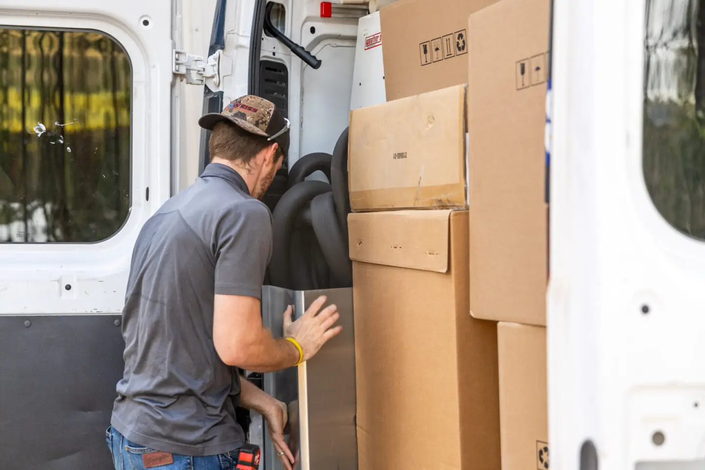 A Weiss Air Conditioning & Plumbing team member loading high-efficiency HVAC equipment and supplies into a van for a local installation project.