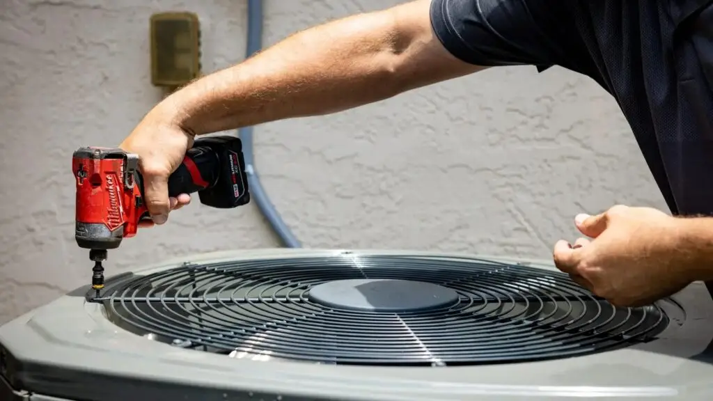 A Weiss Air Conditioning & Plumbing technician performing maintenance on an outdoor AC unit using professional power tools in Montgomery County.