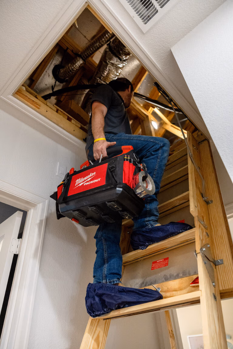 Licensed HVAC tech from Weiss Air Conditioning & Plumbing going into a customer's attic for preventative maintenance in Montgomery, TX.